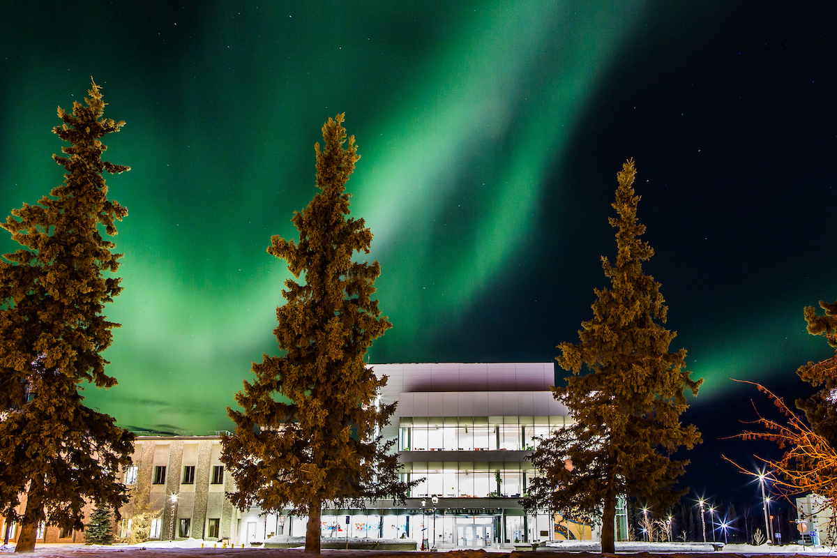 The aurora creates a dynamic display behind the ū컨F Murie Building on upper campus.
